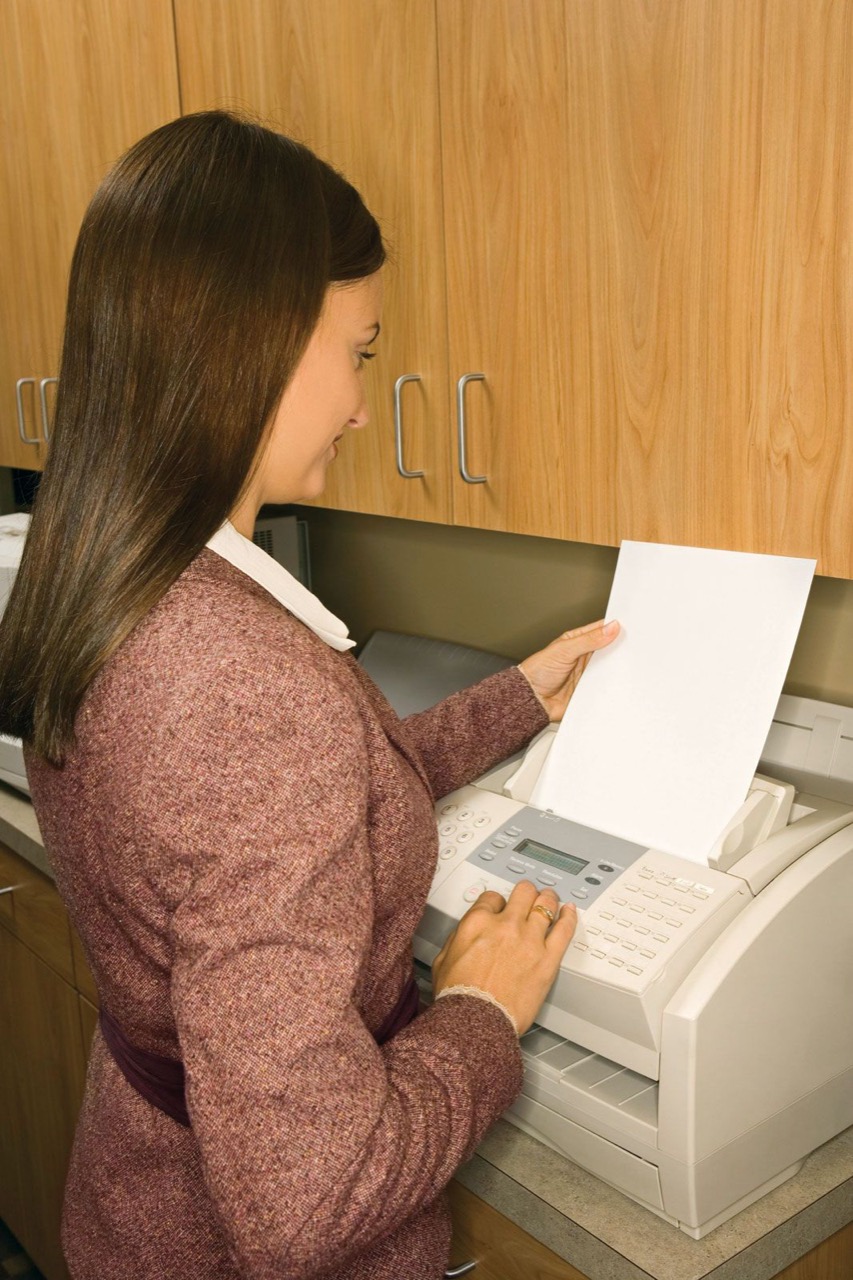 Mulher enviando um fax num escritório